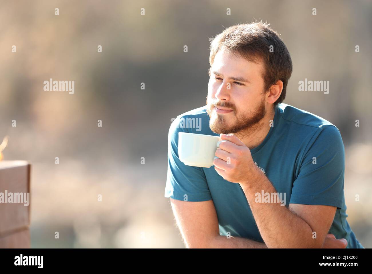 Mann, der in der Natur einen Kaffeebecher hält und dabei die Aussicht betrachtet Stockfoto