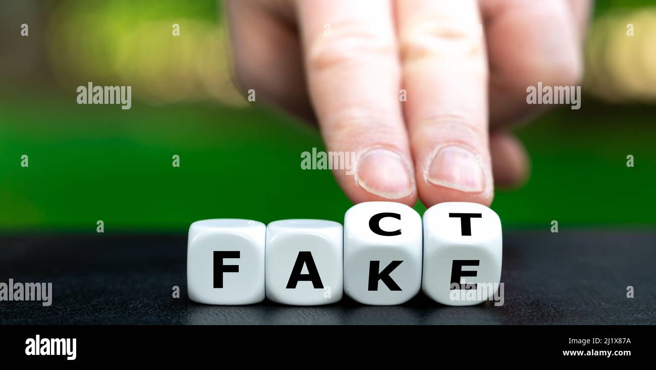 Hand dreht Würfel und ändert das Wort fake in Fakt. Stockfoto