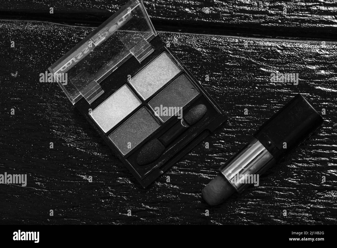 Kosmetik auf einem schwarzen, Nagellack, Lidschatten-Palette, Lippenstift, Pinsel, Parfume Stockfoto