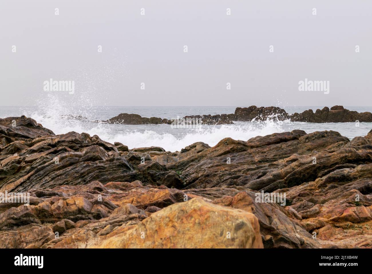 Meeresbrause, brechende Wellen an Felsküsten, anschwellen Energie an der Küste. Meeresenergie bei hohen Gezeiten. Meer- oder Playa-Themen mit Felsen und Wellen. Stockfoto