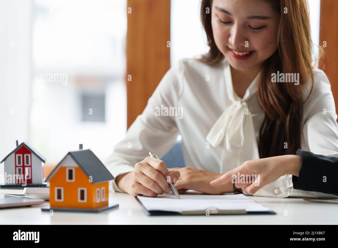 Nahaufnahme der Geschäftsfrau, die auf den Kauf eines Hauses hinweist und eine Vereinbarung unterzeichnet. Konzept des Bankleiters. Stockfoto