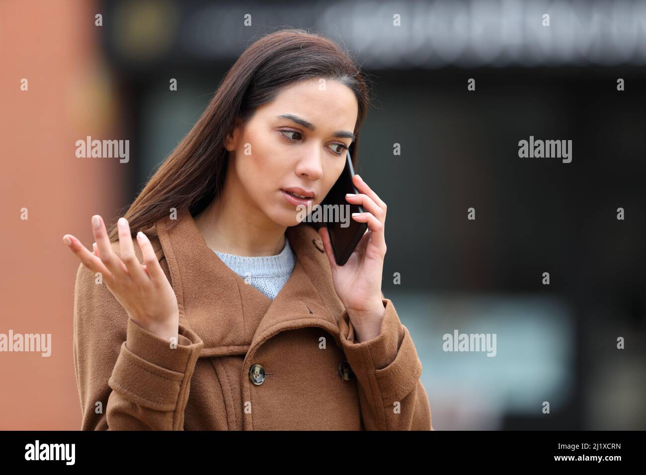 Wütende Frau auf der Straße, die sich über das Mobiltelefon beschwerte Stockfoto