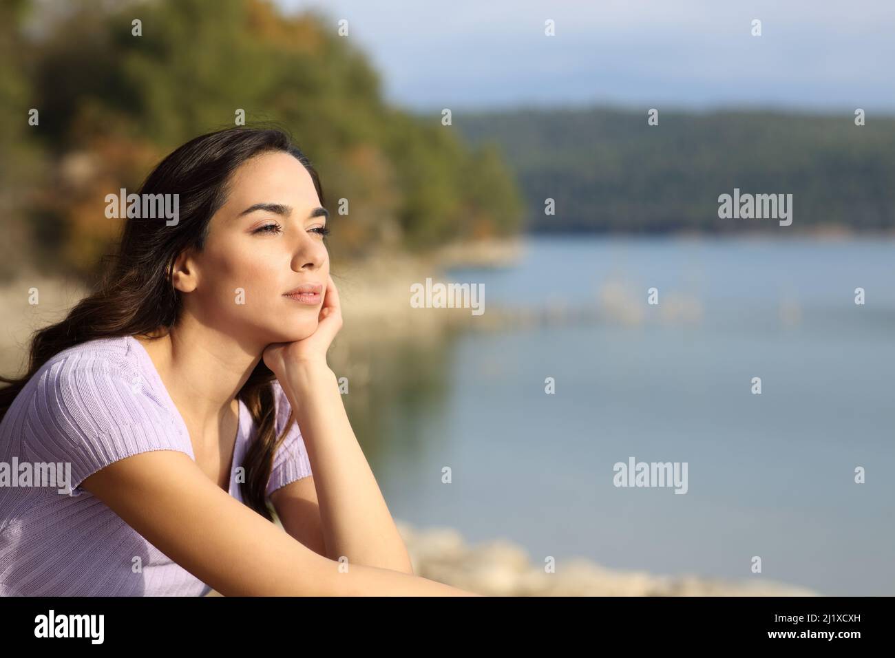 Entspannte Frau, die den Blick auf den See betrachtet und sich im Urlaub ausruhen kann Stockfoto