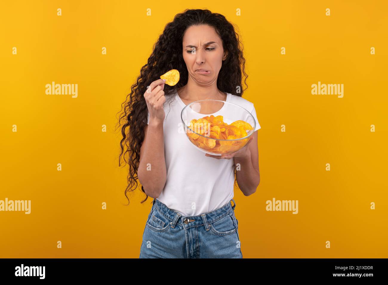 Verwirrte Junge Dame, Die Unsalzige Kartoffelchips Isst Stockfoto