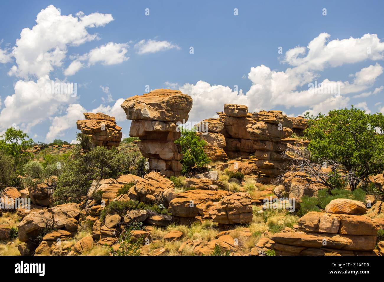Zerklüftete Steinsäulen aus verwittertem Quartzit in den Magaliesberg-Bergen Südafrikas mit geschwungenen Wolken im Hintergrund Stockfoto