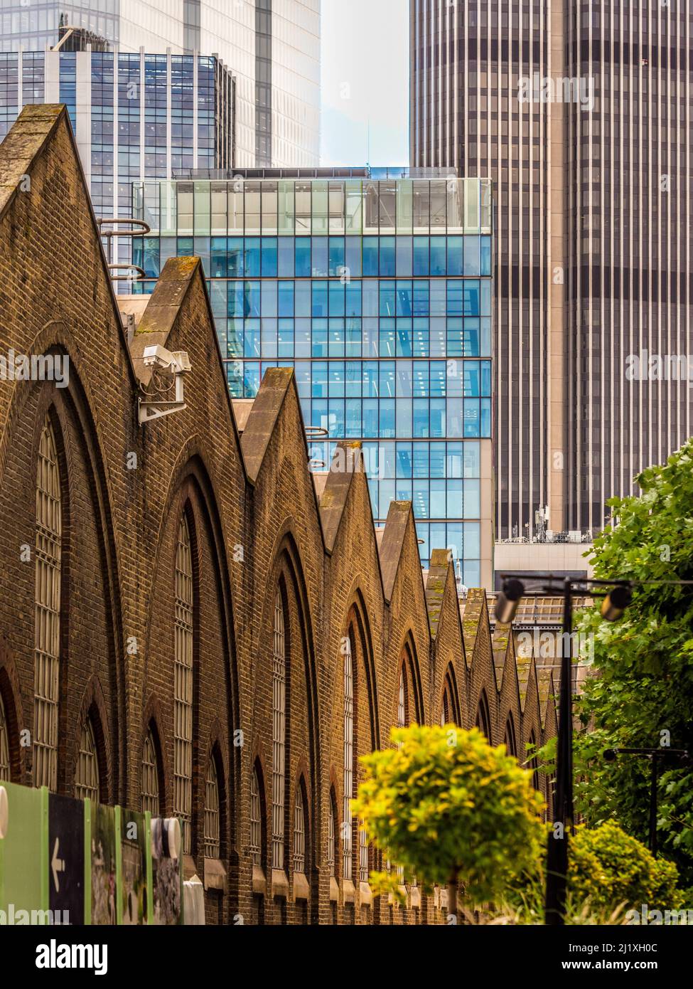 Viktorianische Backsteinfassade façade der Liverpool Street Station von der Sun Street Passage aus gesehen, mit modernen Hochhäusern in der Ferne. London. Stockfoto