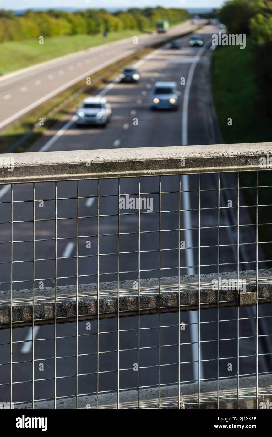 Blick über einen Zaun auf einer Brücke über eine Hauptstraße in Großbritannien. Stockfoto