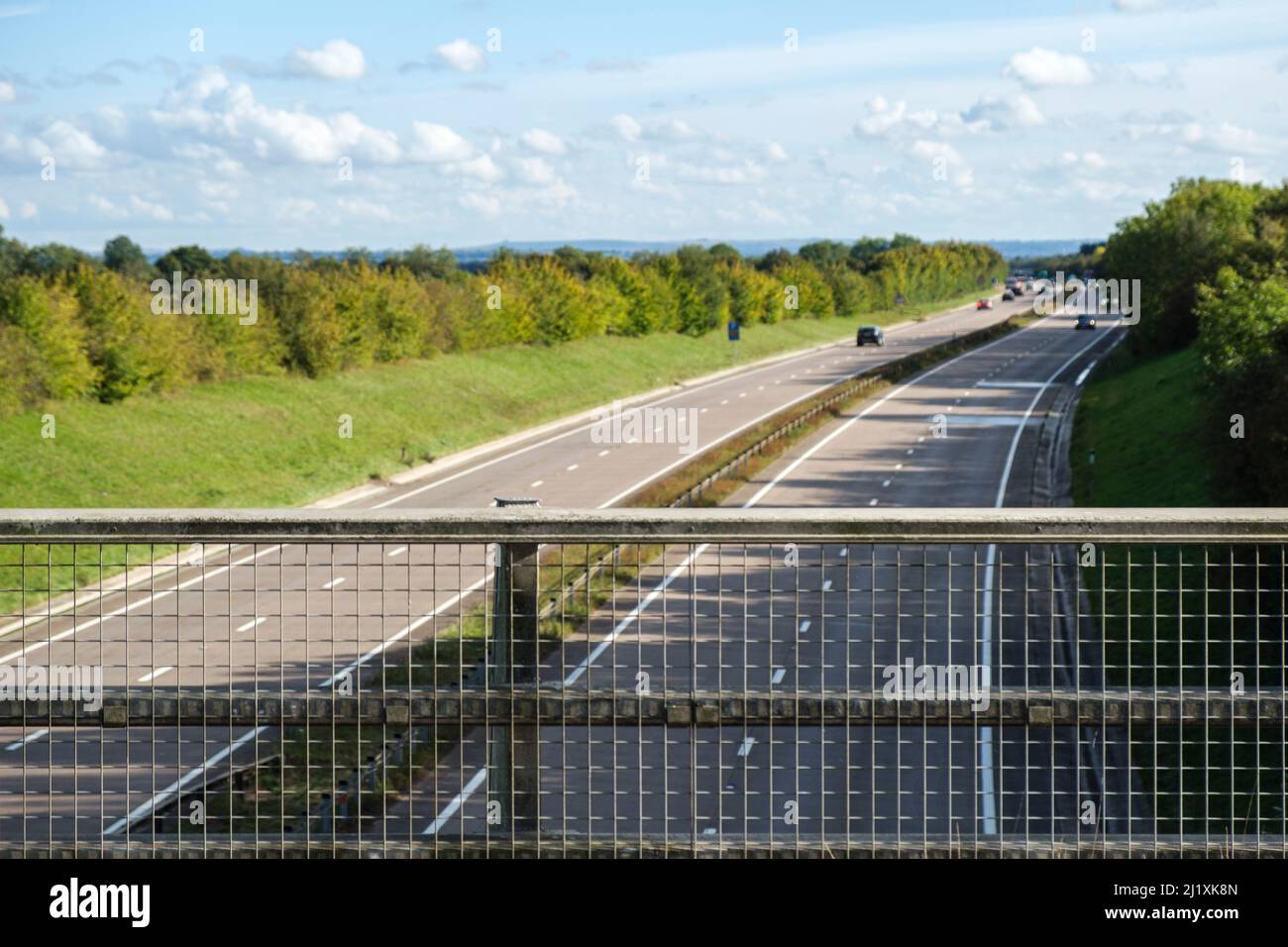Blick über einen Zaun auf einer Brücke über eine Hauptstraße in Großbritannien. Stockfoto