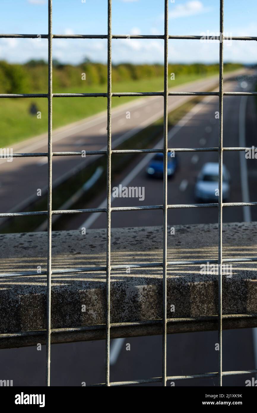 Blick über einen Zaun auf einer Brücke über eine Hauptstraße in Großbritannien. Stockfoto