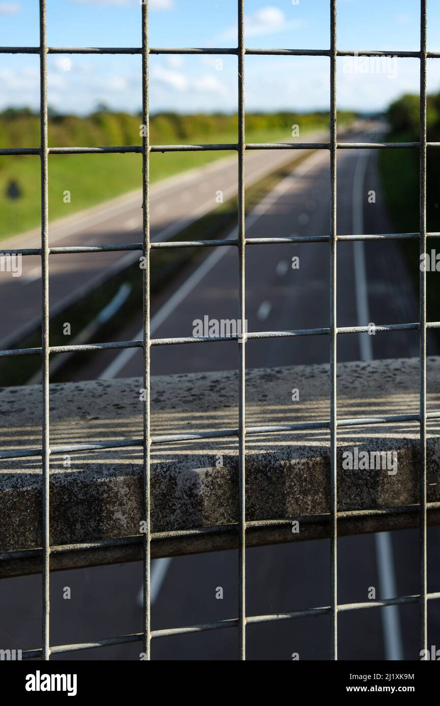 Blick über einen Zaun auf einer Brücke über eine Hauptstraße in Großbritannien. Stockfoto