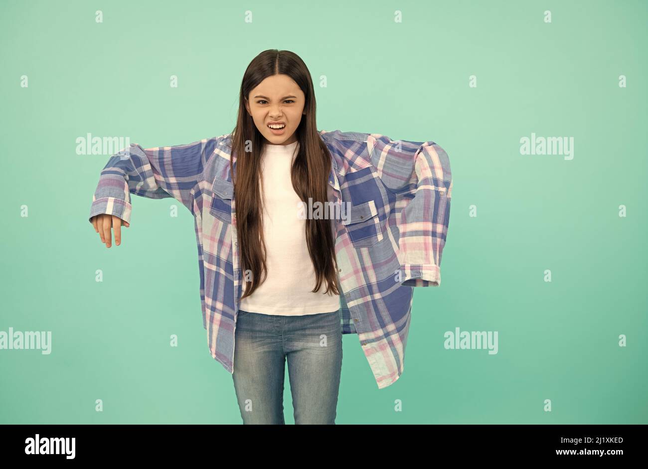 Es ist groß. Unglückliches Mädchen versuchen auf kariertes Hemd. Mädchen Kind blauer Hintergrund. Teenager-Mode Stockfoto