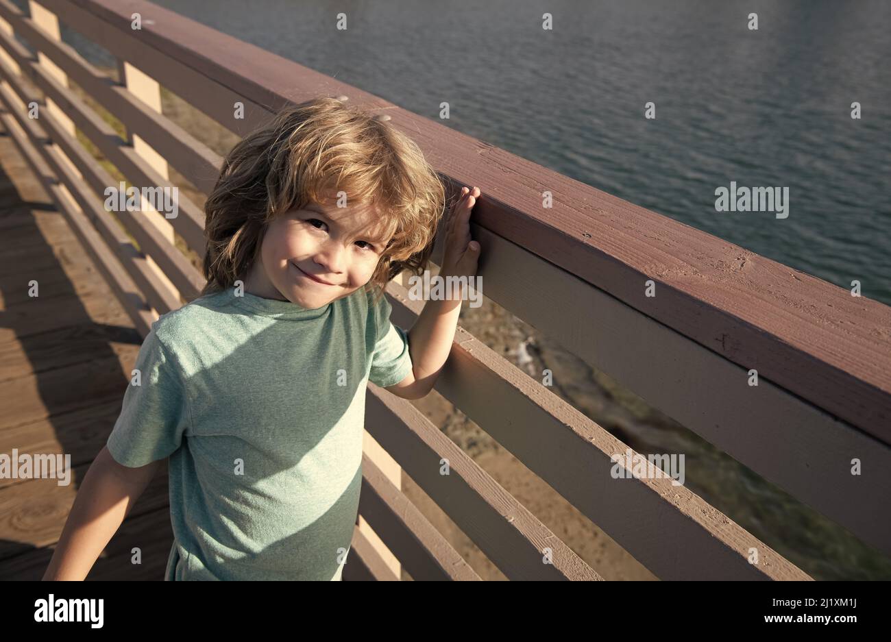 Erholungsurlaub. Fröhlicher Junge Kind steht am Geländer der Promenade. Freizeit. Sommerurlaub Stockfoto