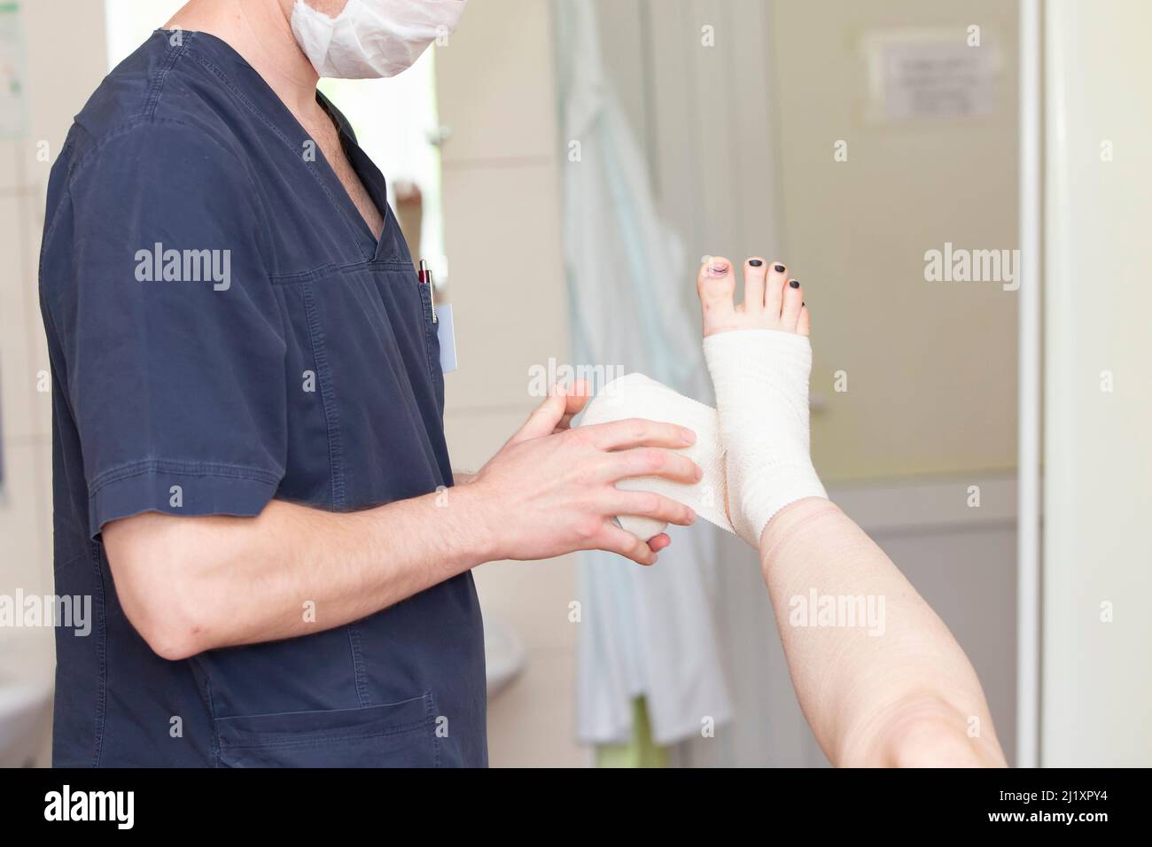 Der Arzt verband das Bein des Patienten. Chirurg und Patient nach Venenoperation. Stockfoto