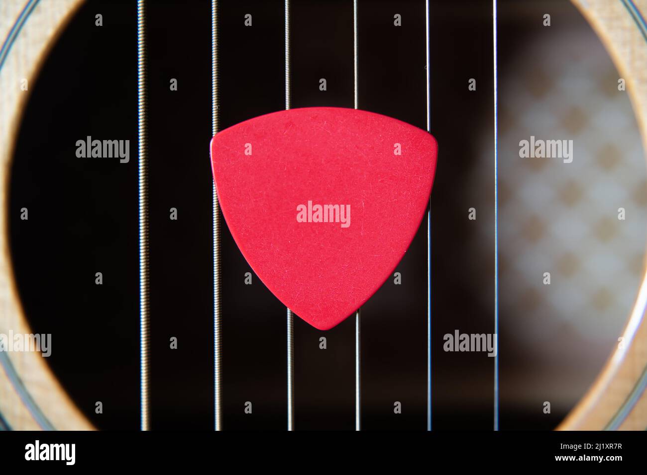 Rote Gitarre Pick auf einem akustischen Gitarre Sound Loch Stockfoto Rote Gitarre Pick auf einem akustischen Gitarre Sound Loch Stockfoto
