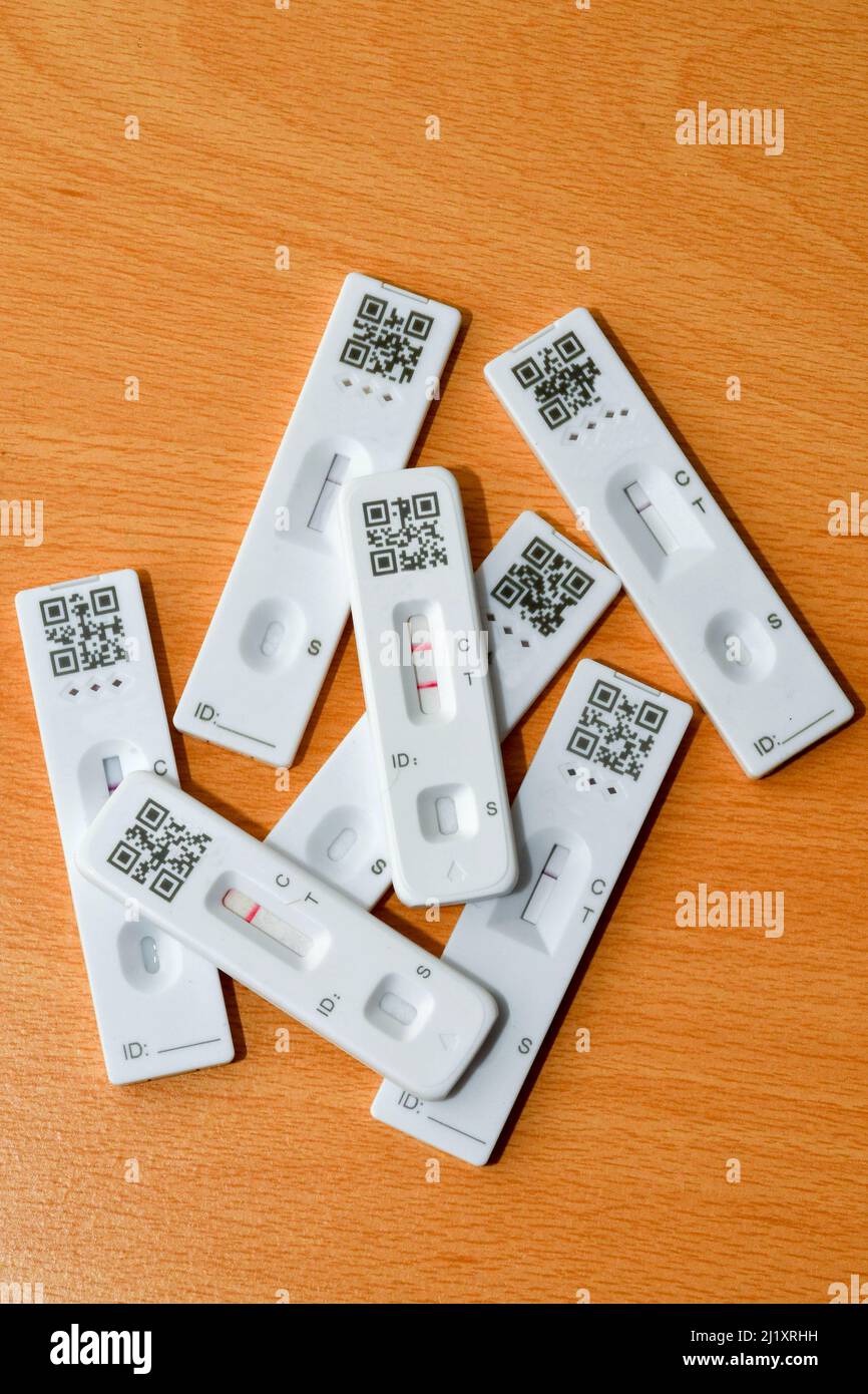 Positives Ergebnis bei einem lateralen Durchflusstest zusätzlich zu negativen Testergebnissen. Mit nicht identifizierbaren QR-Codes. Keine Personen. Stockfoto