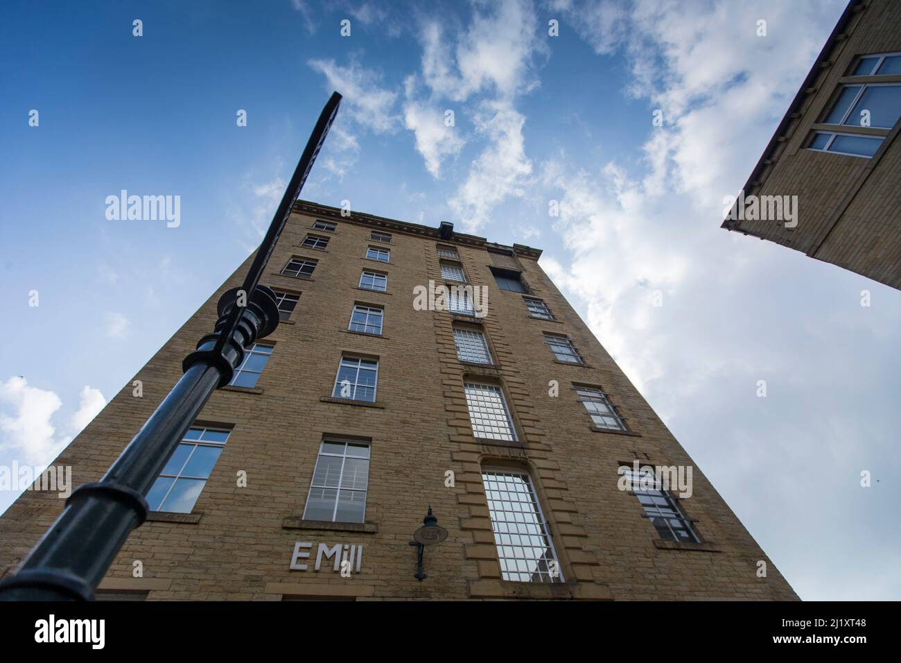 Dean Clough in Halifax, Calderdale, West Yorkshire, England, ist eine Gruppe von großen Fabrikgebäuden, die in den Jahren 1840s bis 60s für Crossley's Teppiche gebaut wurden und zu einer der größten Teppichfabriken der Welt wurden (eine halbe Meile lang mit 1.250.000 Quadratfuß (116.000 m2) Grundfläche). Nach Jahren rückläufiger Produktion schloss es 1983, als es von einem Konsortium unter der Leitung von Sir Ernest Hall gekauft wurde, das die denkmalgeschützte Stätte für verschiedene kommerzielle und kulturelle Zwecke entwickelte. Es gilt heute als ein führendes Beispiel für eine erfolgreiche Stadterneuerung.Dean Clough befindet sich auf der Nordseite von Halifax in der Nähe der V Stockfoto