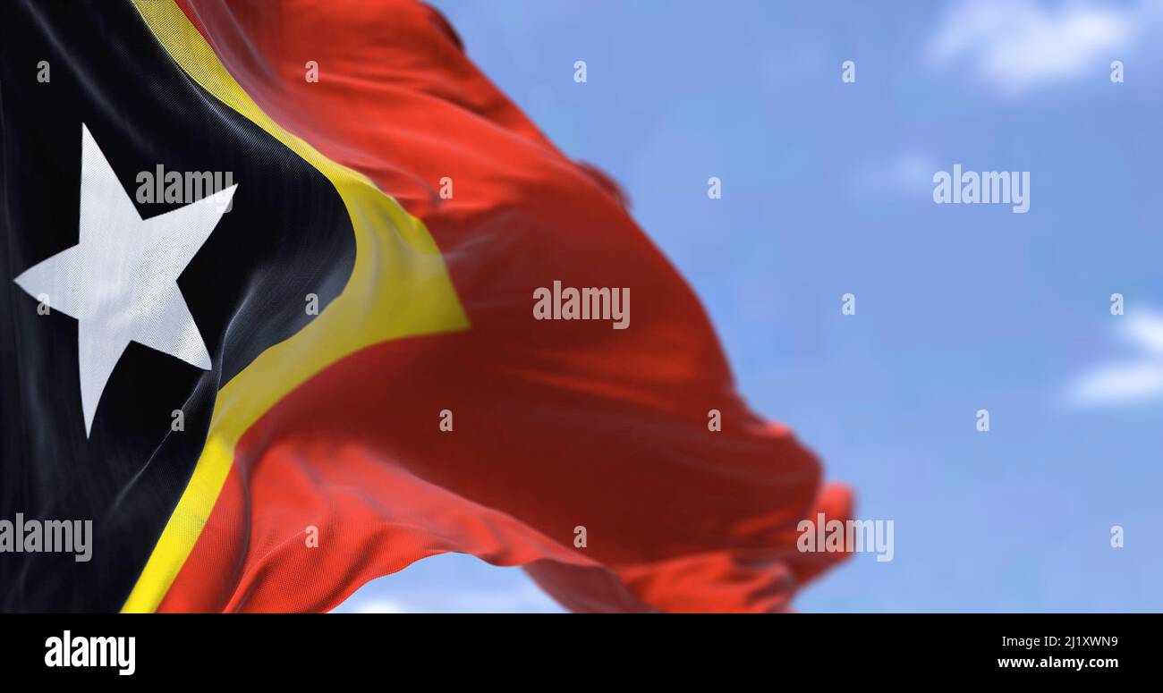 Detail der Nationalflagge von Osttimor, die an einem klaren Tag im Wind winkt. Osttimor ist ein Inselstaat in Südostasien. Selektiver Fokus. Stockfoto