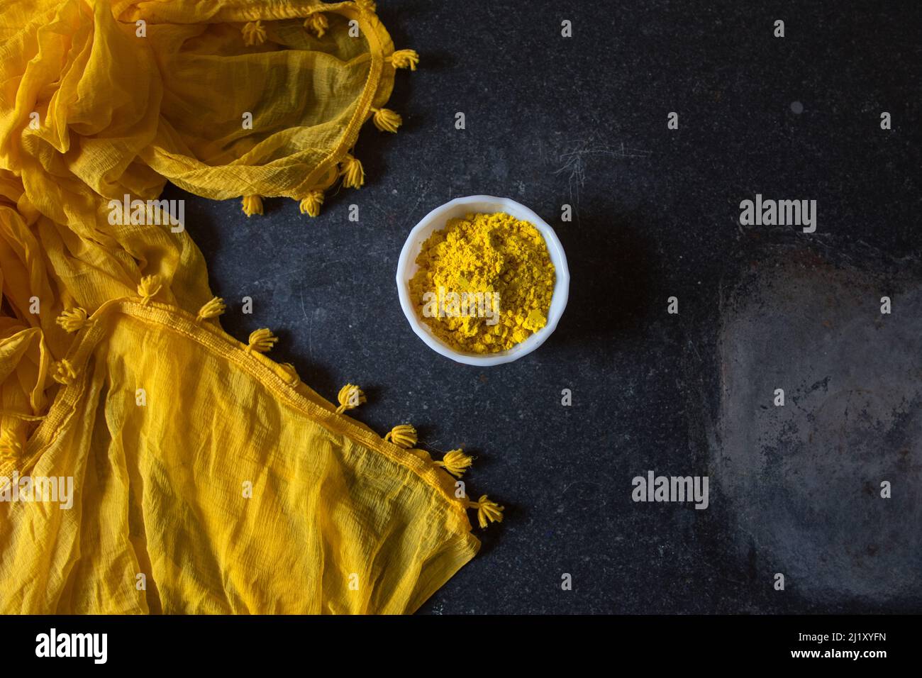 Gulal oder holi Festival gelbe Pulverfarbe in Schale auf dunklem Hintergrund. Stockfoto