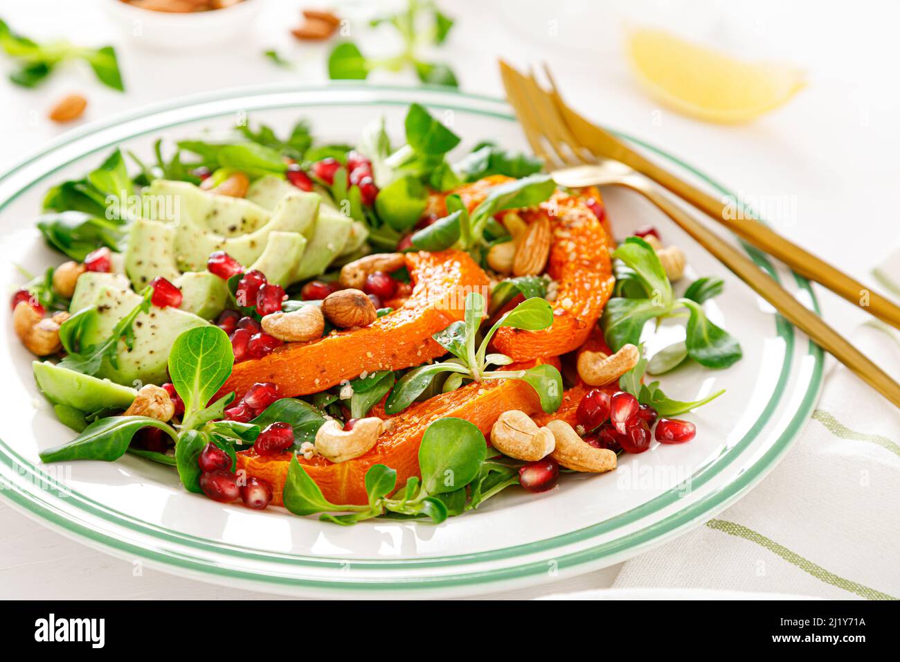 Frischer Gemüsesalat mit Lammsalat, gebackenem Butternusskürbis oder Kürbis, Avocado, Granatapfel, Cashew und Mandelnüssen. Gesunde vegetarische Kost Stockfoto