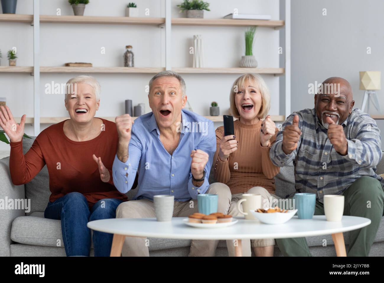Emotionale multirassische ältere Menschen, die Fußballspiele im Fernsehen ansehen Stockfoto