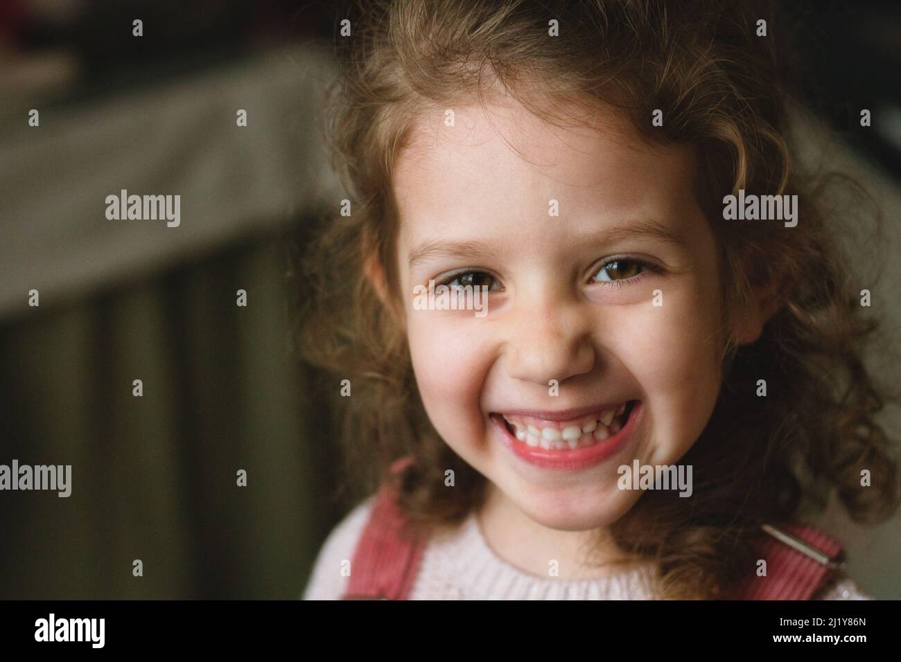 Nahaufnahme eines niedlichen kleinen weißen kaukasischen Mädchens mit einem frechen Lächeln und Ausdruck auf ihrem Gesicht, das direkt auf die Kamera blickt Stockfoto