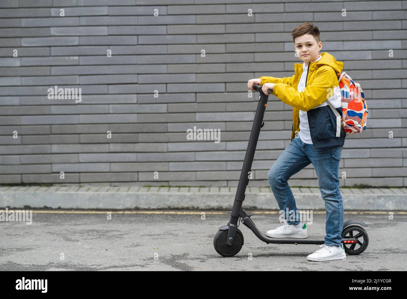 Schöner Junge auf Elektroroller im Freien Stockfoto
