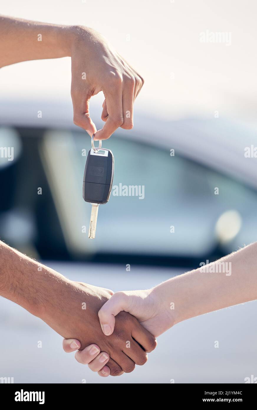 Die weniger befahrene Straße ist aus einem bestimmten Grund weniger befahrene Straße. Aufnahme einer nicht erkennbaren Frau, die einem Mann die Hände schüttelt, als sie einen Autoschlüssel vor die Tür bekommt. Stockfoto