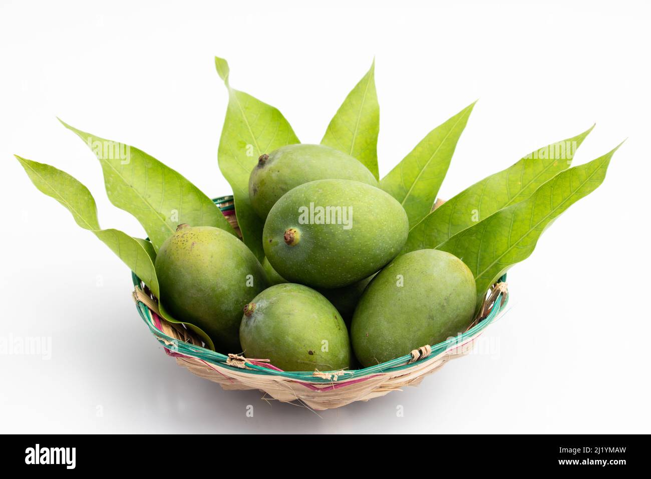 Nahaufnahme Von Frischen Rohen Grünen Mangos, Auch Kacha Khatta Aam Genannt, Mit Blättern Im Bambuskorb. Isoliert Auf Weißem Hintergrund Mit Kopierbereich Stockfoto