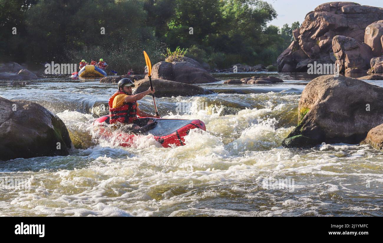 Ein Mann rudert aufblasbares Packfloß auf Wildwasser des Gebirgsflusses. Konzept: Sommer Extremwassersport, aktive Erholung, Extremrafting. Stockfoto