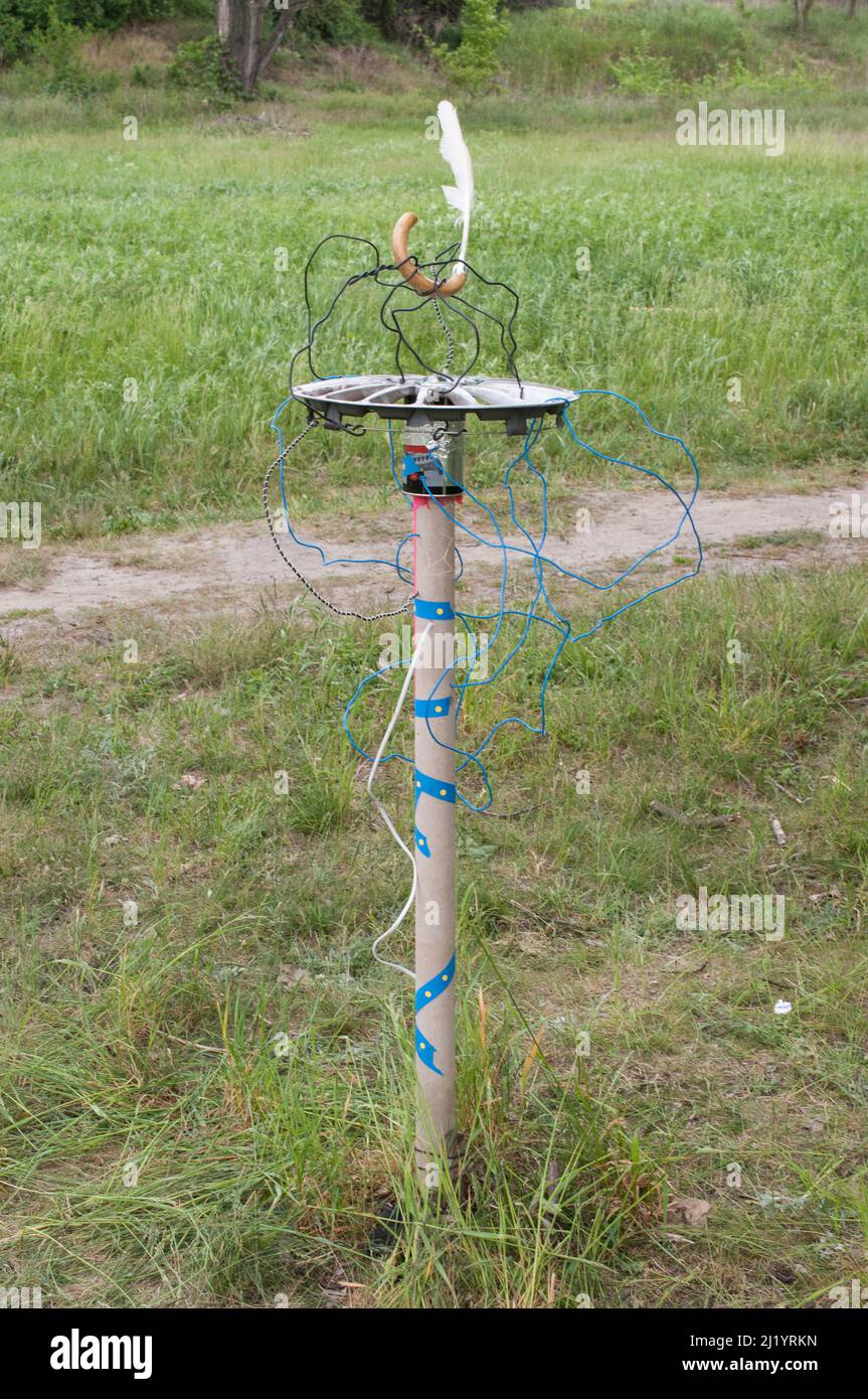 Land Art Intervention, recycelte Elemente Objekt mit Kartonschlauch, Karwheelabdeckung, Drähte und Kabel, Feder außen in der Natur Stockfoto