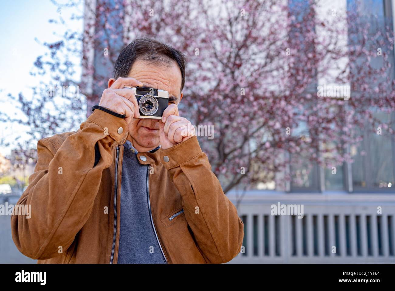 Ein älterer Mann wird während der Dreharbeiten mit seiner alten Filmkamera fotografiert. Stockfoto