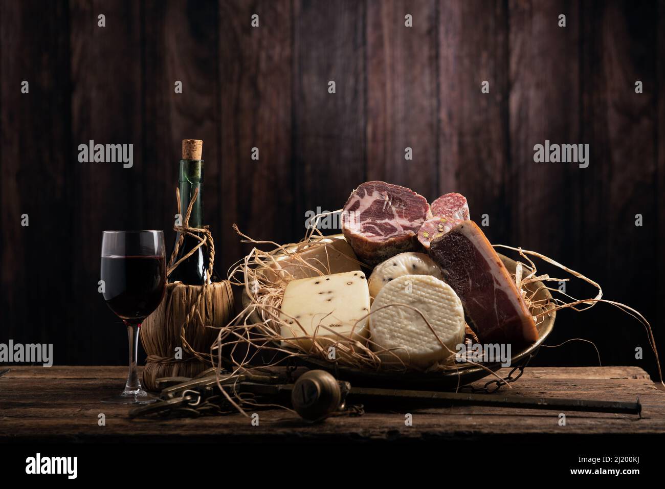 Verschiedene hausgemachte Käse, Salumi auf Holztisch mit einem Holzhintergrund. Nahaufnahme Stockfoto