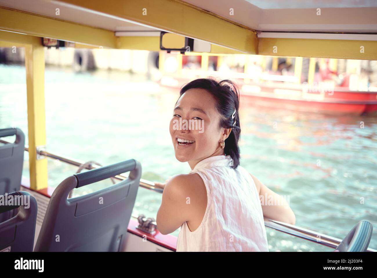 Es ist der perfekte Tag für eine Bootsfahrt. Ein Porträt einer attraktiven jungen Frau, die tagsüber auf einer Fähre die Stadt allein erkundet. Stockfoto