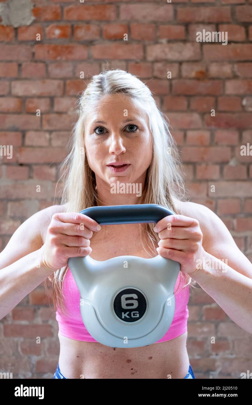 Junge muskulöse Frau macht High-Pull-Übung mit Kettlebells beim harten Training in der Garage Fitnessraum. Hochwertige Fotos Stockfoto