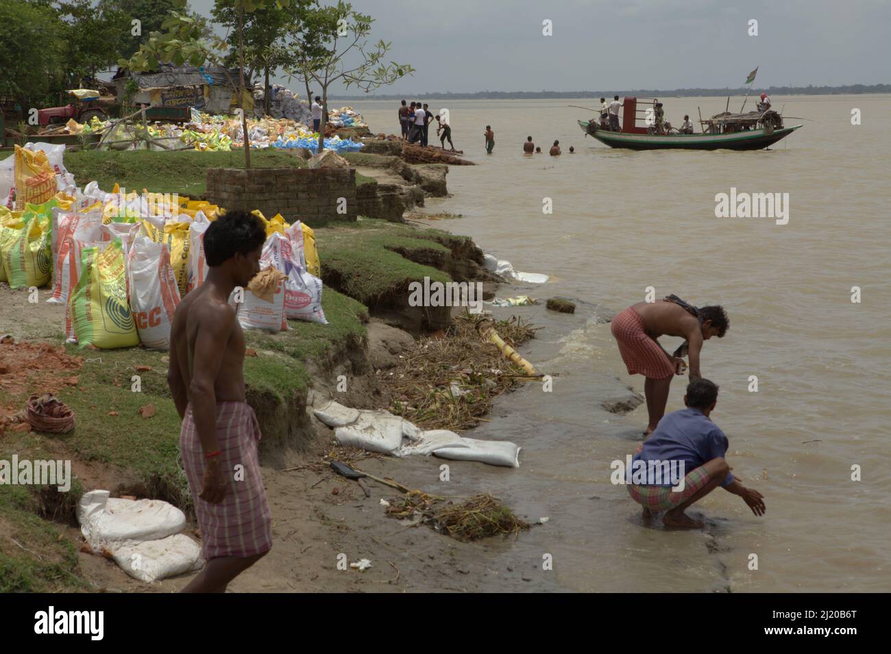 Arbeiter eines Flussabriebschutzprojekts, das sich am Ufer des Rupnarayan-Flusses waschente, als ein örtliches Fährschiff in Tamluk, Purba Medinipur, Westbengalen, Indien, landen wollte. Tamluk, in der Antike als Tamralipti bekannt, war das Haupttor für Nalanda-gebundene buddhistische Pilger, die aus dem Meer aus Kuang-tung (heute Guangzhou, China) kamen, einem langen Segel, das einen Transit in den Häfen des Srivijaya-Imperium entlang der heutigen Straße von Malacca benötigen würde. „Am achten Tag des zweiten Monats im vierten Jahr der Hsien-Heng-Periode (673 n. Chr.) kam ich in Tamralipti an.“ Stockfoto