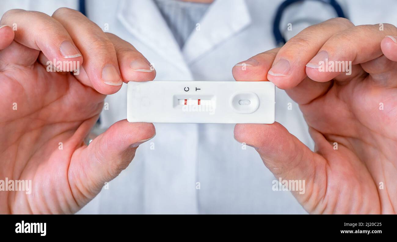 Der Arzt hält eine positive Express-Testkassette für Hepatitis oder Coronovirus in den Händen Stockfoto