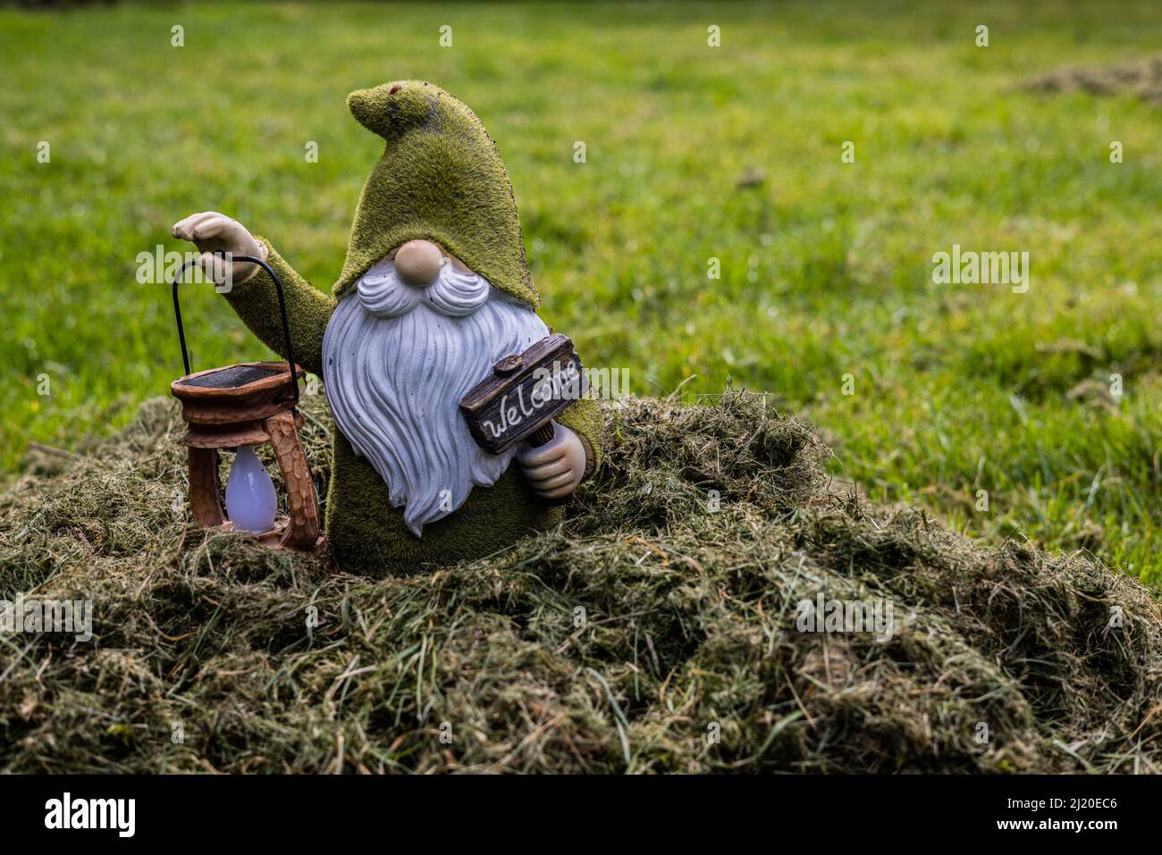 Mann bis zur Hüfte im Müll vom Hof. Mit Laterne und Willkommensschild. Stockfoto