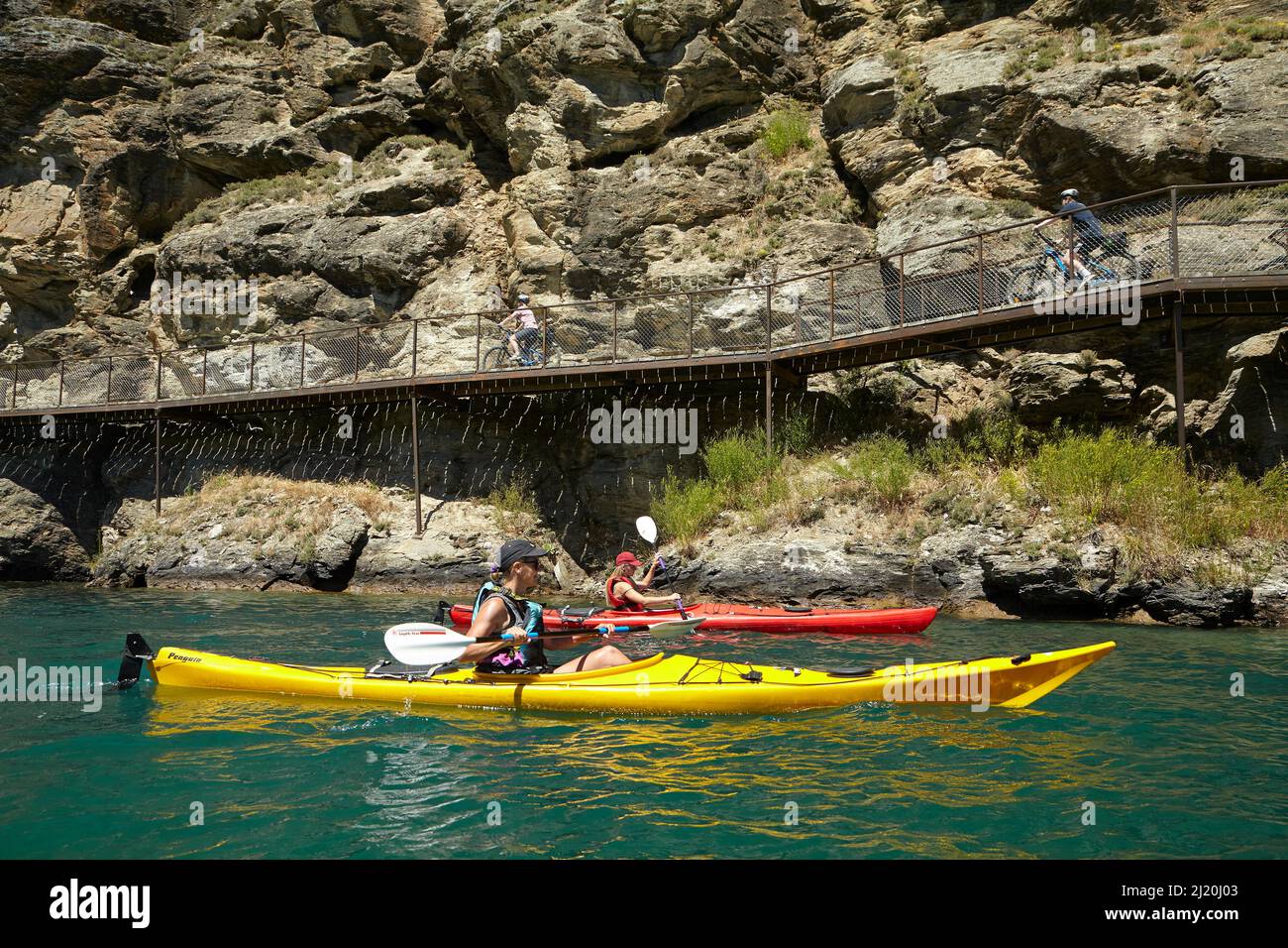 Radfahrer auf der Freischwinger-Brücke auf dem Lake Dunstan Cycle Trail und Kajakfahrer, Lake Dunstan, in der Nähe von Cromwell, Central Otago, Südinsel, Neuseelandl Stockfoto