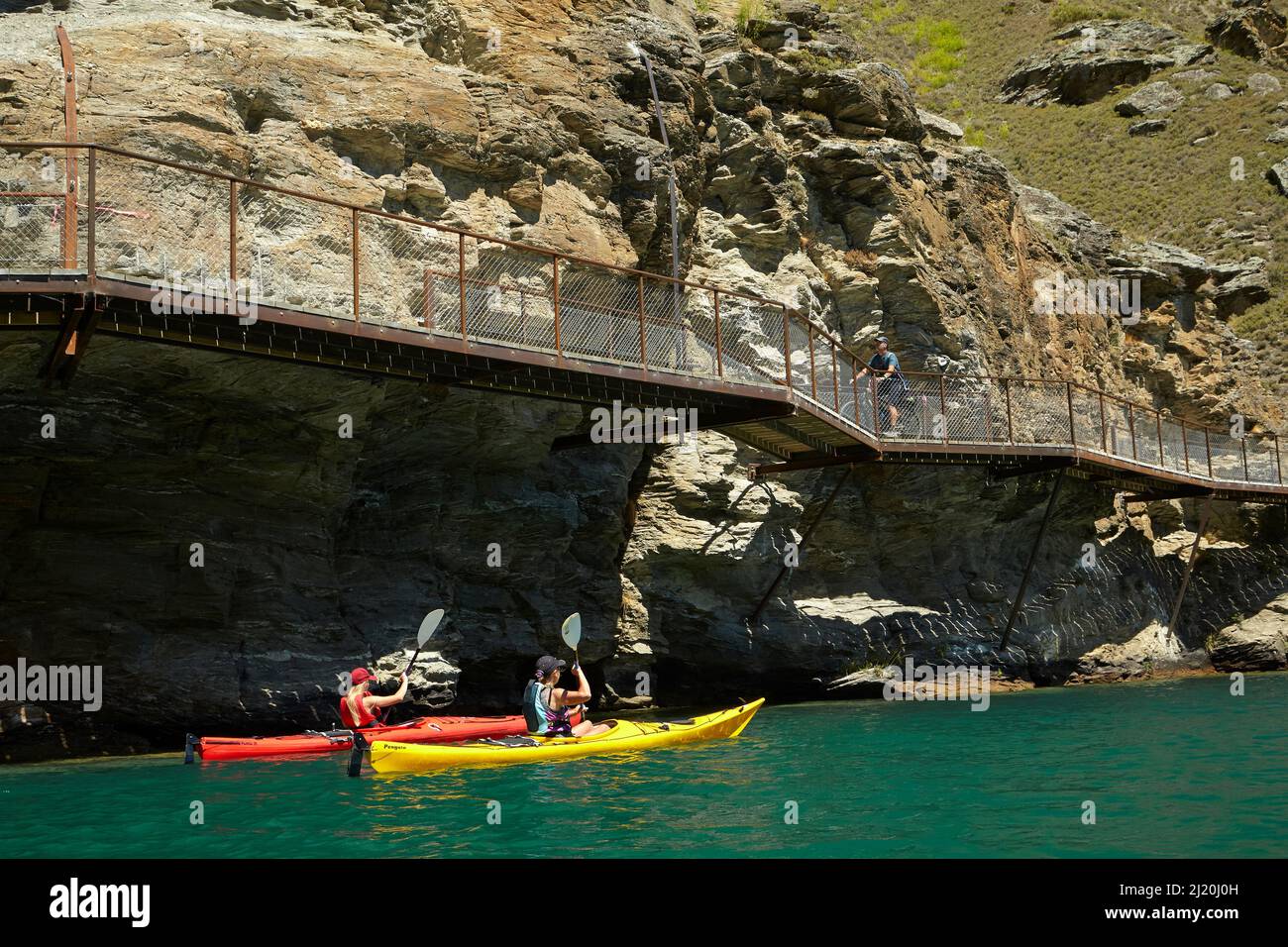 Radfahrer auf der Freischwinger-Brücke auf dem Lake Dunstan Cycle Trail und Kajakfahrer, Lake Dunstan, in der Nähe von Cromwell, Central Otago, Südinsel, Neuseelandl Stockfoto