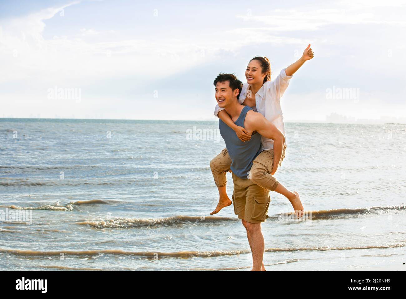 Ehemann trägt Frau auf dem Rücken an einem Sommerstrand - Stock Foto Stockfoto