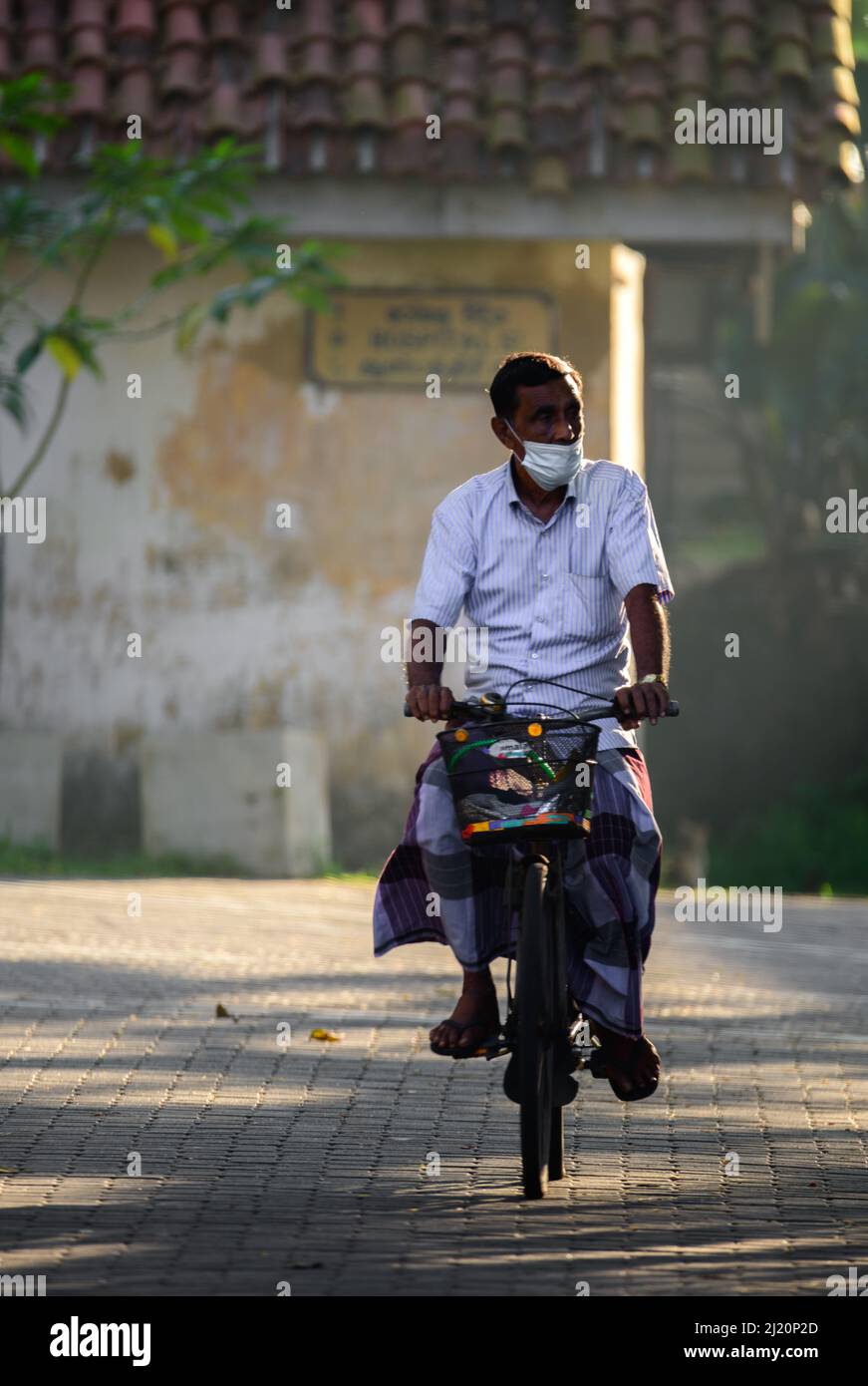 Galle, Sri Lanka - 02 26 2022: Konzept des Alltags in Sri Lanka, ältere Menschen fahren früh morgens mit dem Fahrrad, Stockfoto