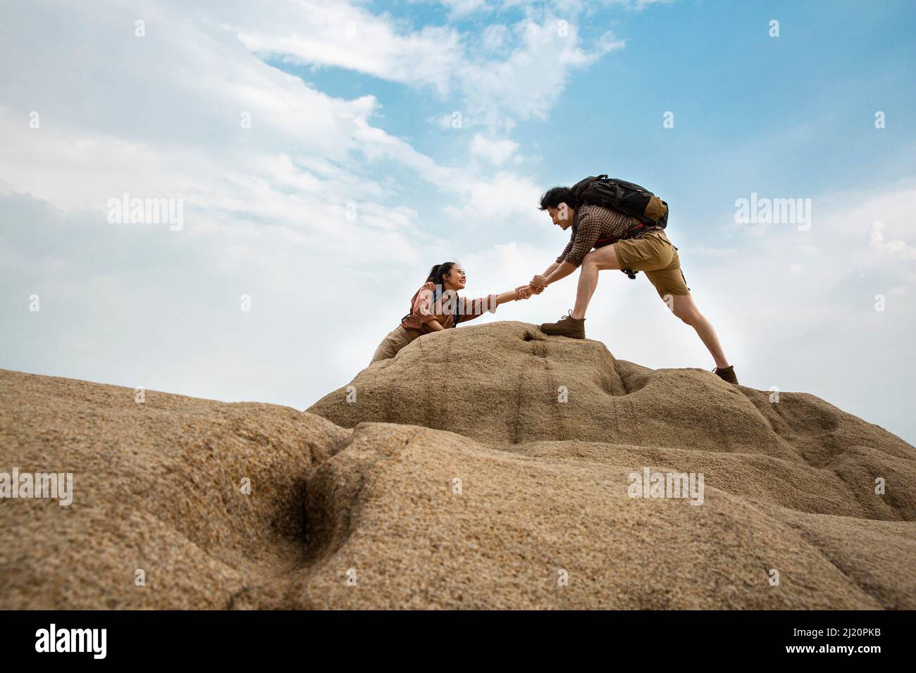 Bergsteiger, die sich gegenseitig auf steilen felsigen Gipfeln helfen, aus der Sicht der niedrigen Winkel - Stock Foto Stockfoto