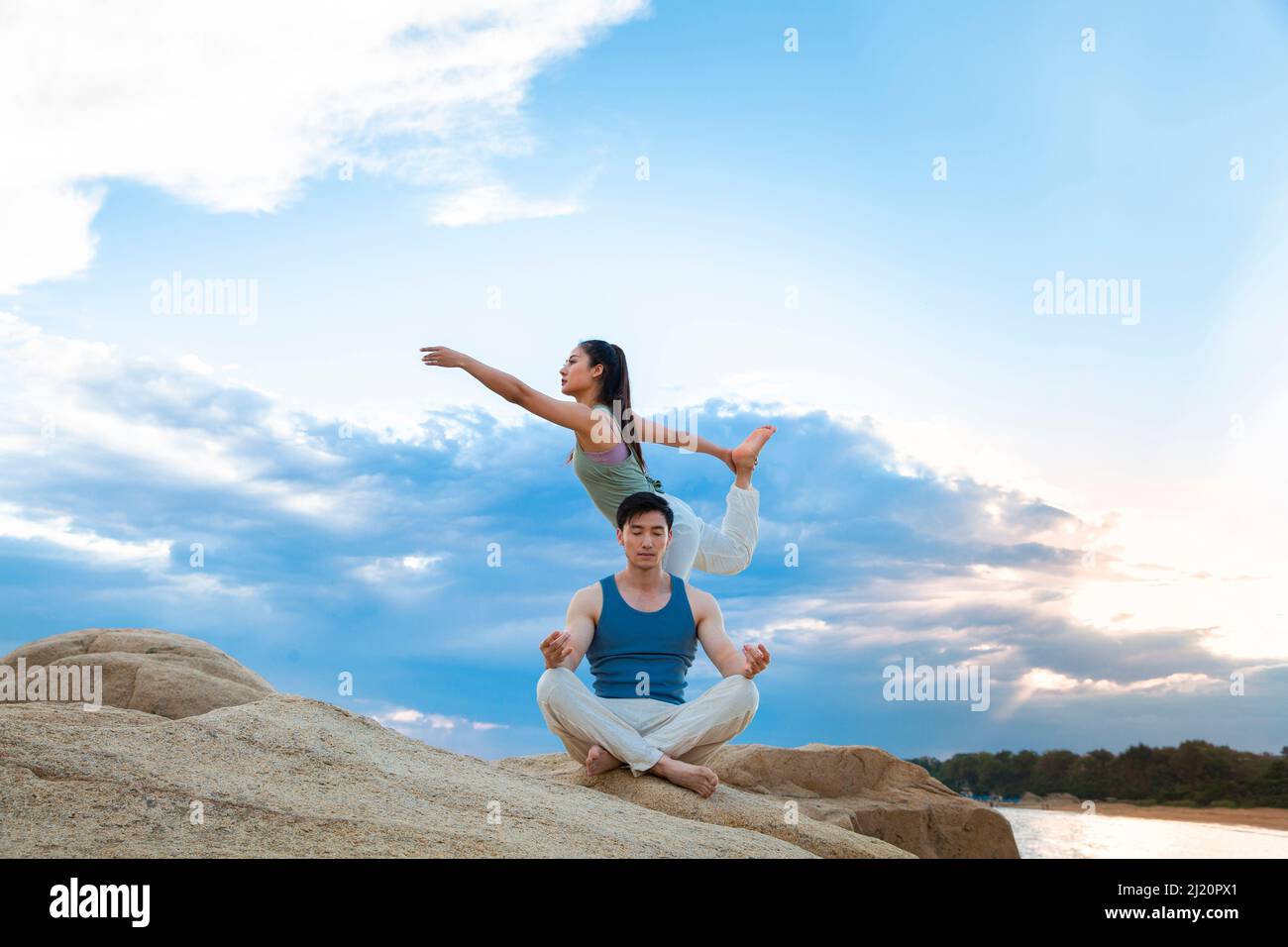 Paare, die Yoga auf den Felsen der Insel praktizieren - Stock photo Stockfoto