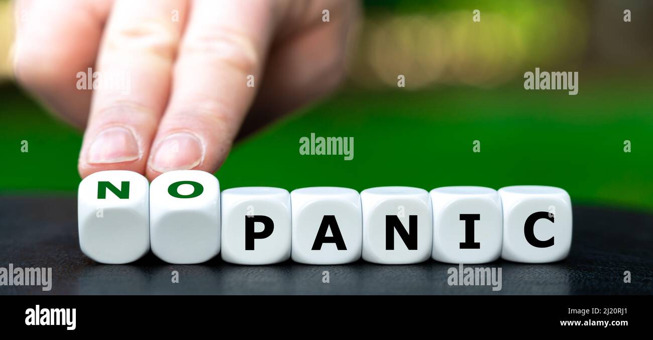Die Hand dreht Würfel und ändert den Ausdruck „Panik“ in „keine Panik“. Stockfoto
