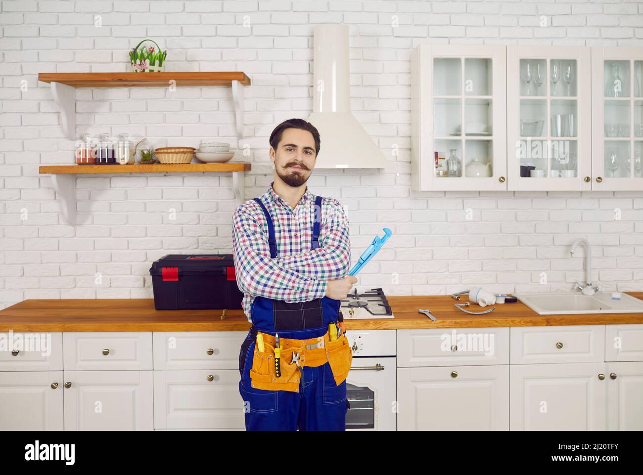 Porträt eines professionellen männlichen Klempners in Overalls, der in der Küche der Wohnung posiert. Stockfoto