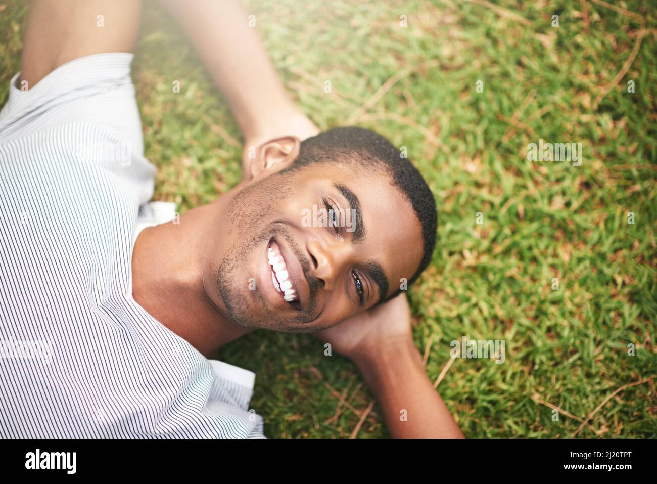 Ich habe die ganze Woche auf diesen Moment gewartet. Aufnahme eines jungen Mannes, der sich im Freien auf dem Gras entspannt. Stockfoto