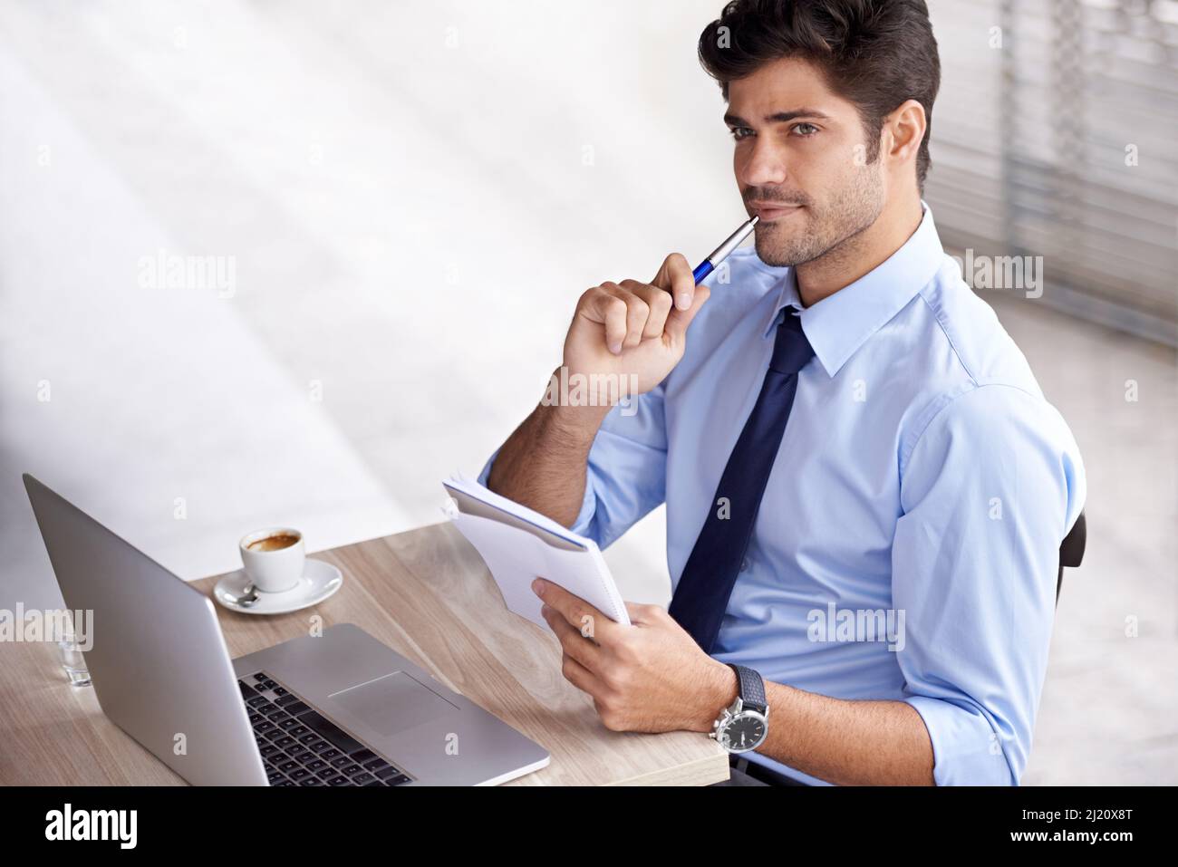 Kaffeeinduzierte Innovation. Ein hübscher junger Geschäftsmann, der mit seinem Laptop und einem Notizblock in einem Café sitzt. Stockfoto
