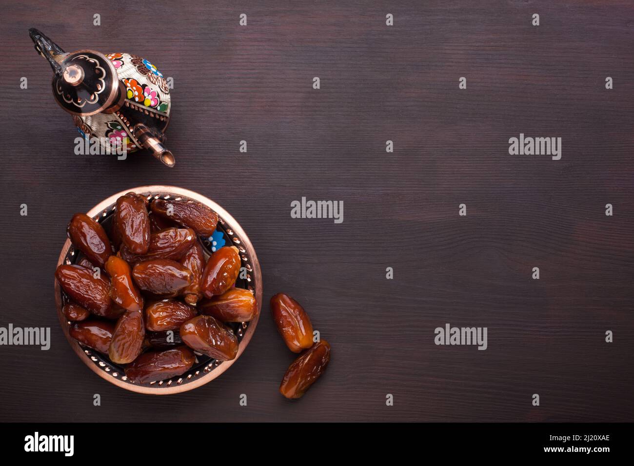 Teller mit Datteln, Kaffeekocher auf dunkelbraunem Holztisch. Ramadan Hintergrund. Draufsicht. Stockfoto