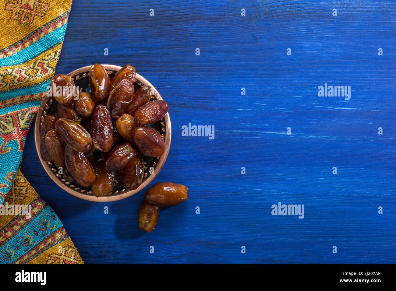 Bronzeteller mit Datteln auf altem blauen Holztisch. Ramadan Hintergrund. Flach liegend. Stockfoto