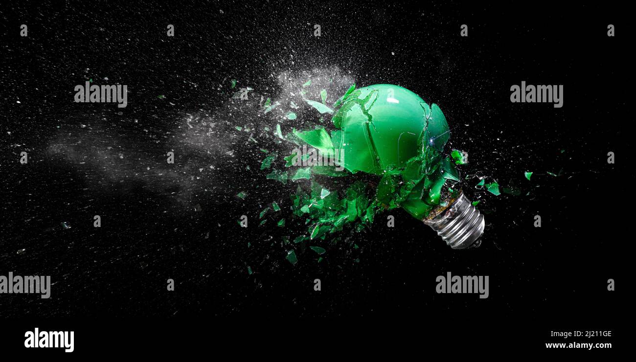 Grüne elektrische Glühbirne explodiert auf schwarz. Stockfoto